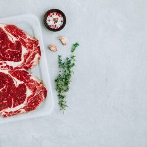 Steak de bœuf haché dans un emballage sous vide avec assaisonnements sur fond de pierre grise, vue du dessus, espace de copie