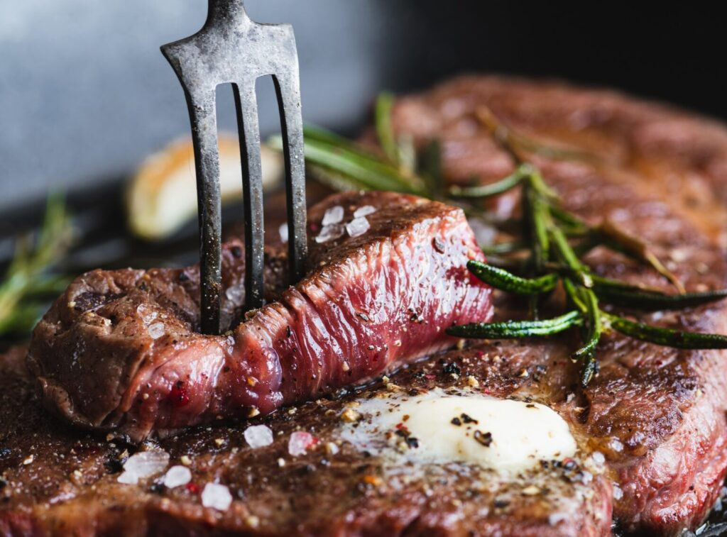 steak de bœuf avec romarin, poivre noir, sel de mer et beurre sur une poêle à grill, focus sélectif