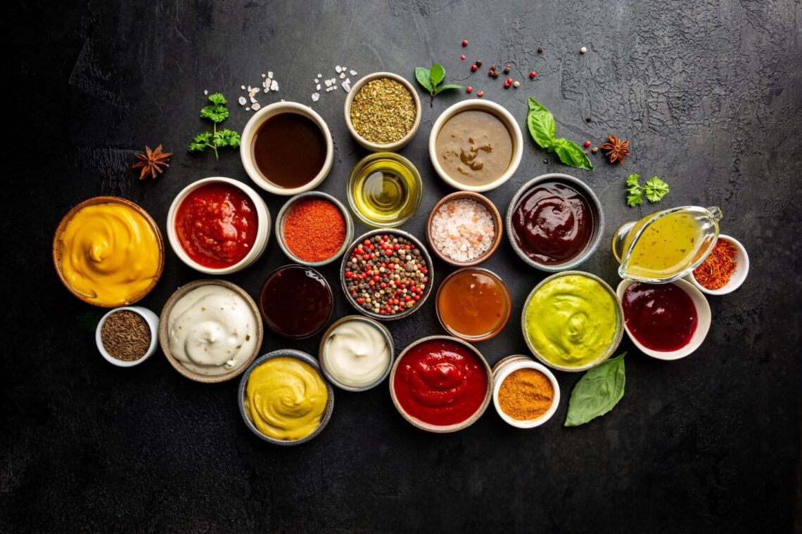 Ensemble de différents bols de diverses sauces de trempette, sur fond sombre, vue de dessus