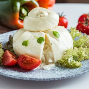 Fromage doux italien à la main frais, boules blanches de burrata ou de fromage de burratine à base de mozzarella et de crème garantie de feuilles de laitue et de tomates rouges